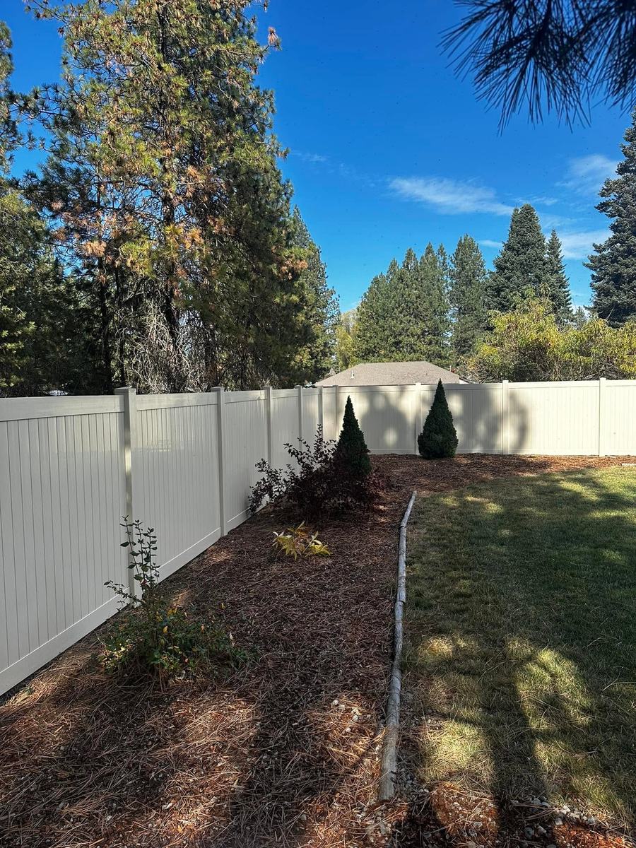 Vinyl privacy fence around a landscaped backyard