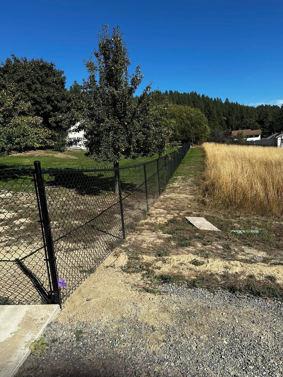 Black chain link fence running along an open field