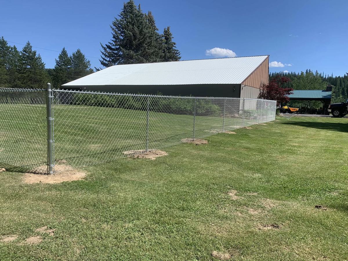 Galvanized chain link fence around a large shop building